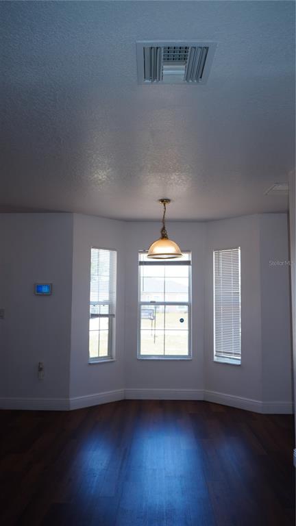 A dining area with a bay window, a hanging light fixture, and dark wood flooring — 1417 SARASOTA DRIVE, KISSIMMEE, FL