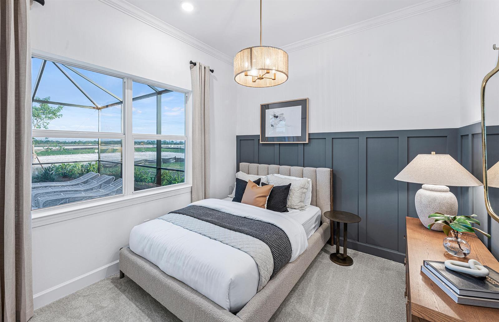 A bedroom features a gray paneled accent wall, a bed, and a window with outdoor views — 19925 Nickel Trail, Punta Gorda FL 33982, PUNTA GORDA, FL