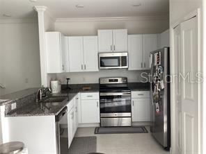 A kitchen features white cabinets, stainless steel appliances, and granite countertops — 17522 NECTAR FLUME DRIVE, LAND O LAKES, FL