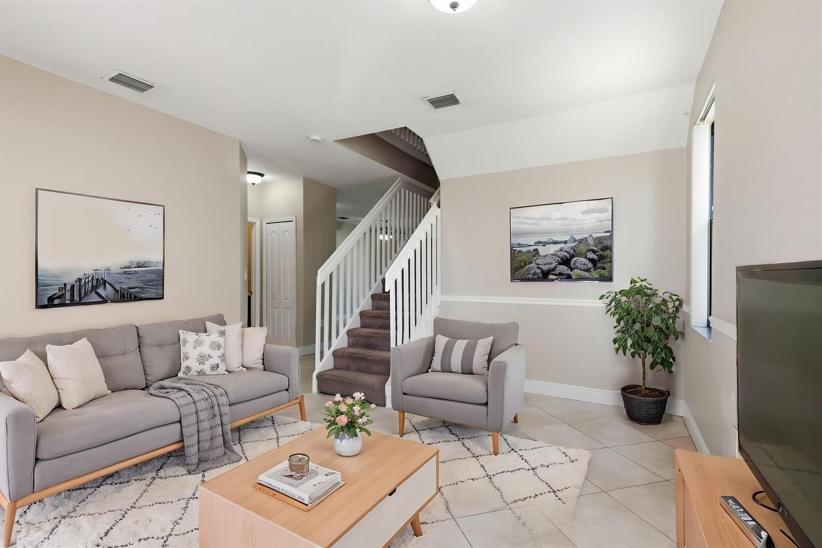 A living room features a gray sofa, armchair, coffee table, and staircase with carpeted steps — 3720 SW 69th Avenue # 3720, Miami FL 33155, MIAMI, FL