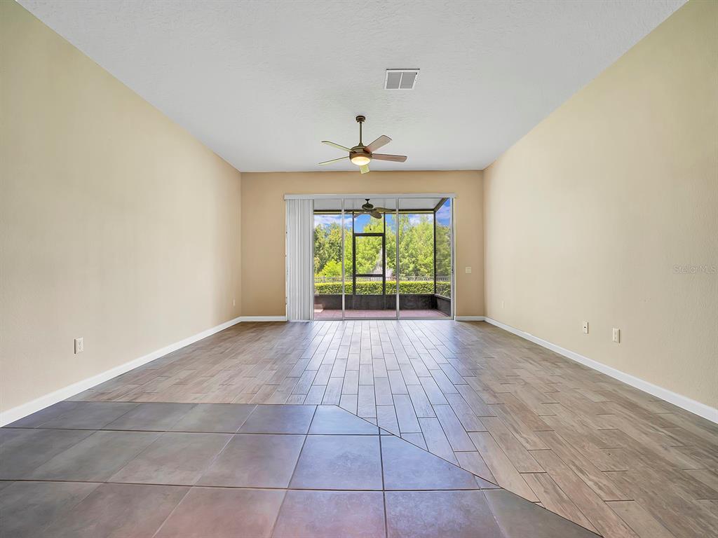A living room features wood-look tile flooring, a ceiling fan, and sliding glass doors to a lanai — 2508 GALLIANO CIRCLE, WINTER PARK, FL