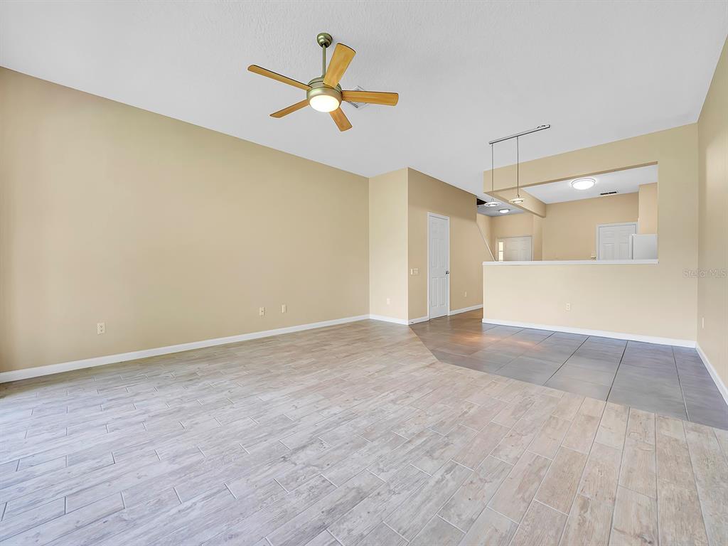 An empty living room features light wood-look tile flooring, a ceiling fan, and beige walls — 2508 GALLIANO CIRCLE, WINTER PARK, FL