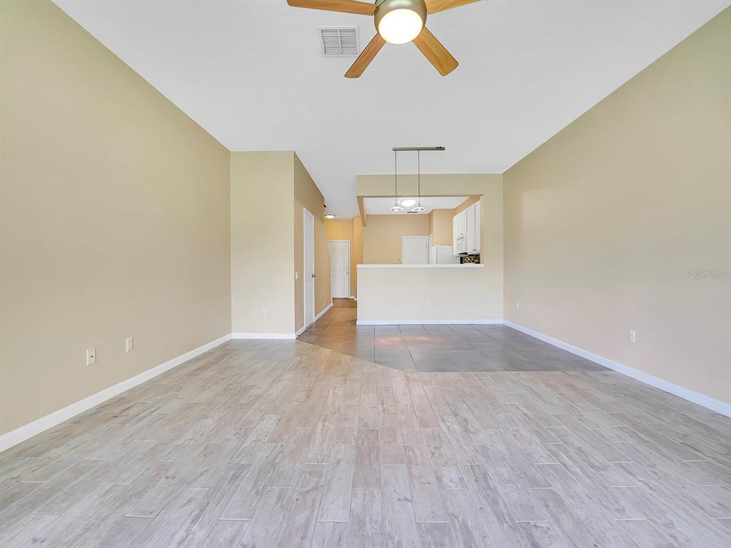 A living room with light wood-look tile flooring transitions to a kitchen with dark tiles — 2508 GALLIANO CIRCLE, WINTER PARK, FL
