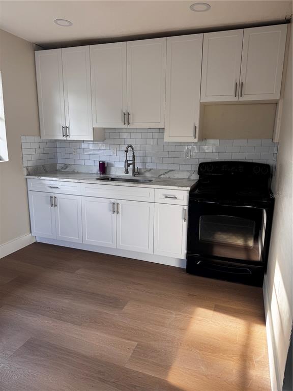 A kitchen features white cabinets, a subway tile backsplash, marble-look countertops, and a black stove — 1204 W ALSOBROOK STREET, PLANT CITY, FL