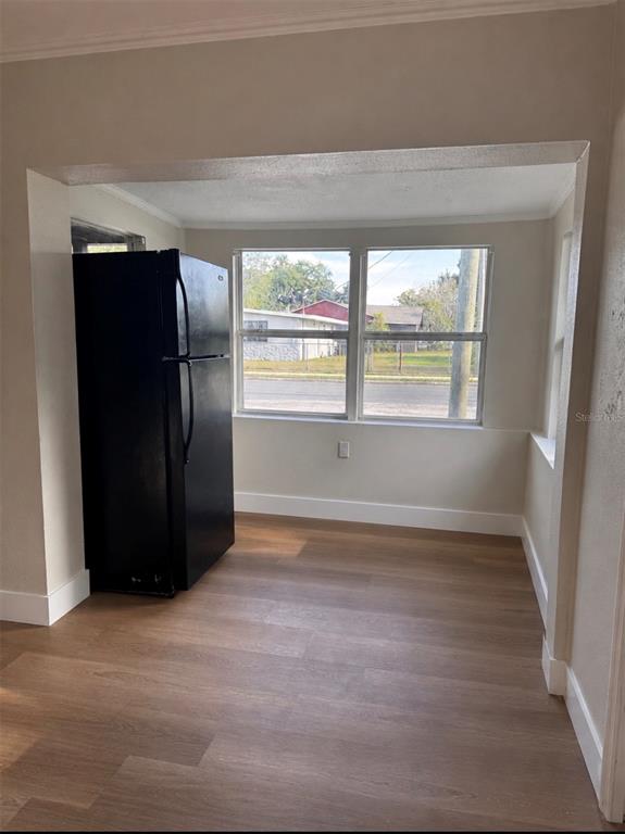 A black refrigerator stands in a room with light wood-look flooring and large windows — 1204 W ALSOBROOK STREET, PLANT CITY, FL