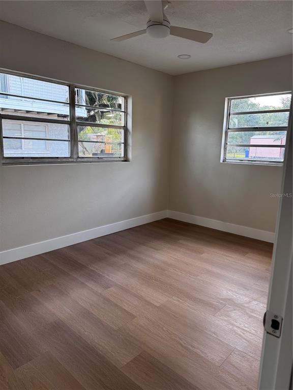 An empty bedroom features light-colored walls, wood-look flooring, a ceiling fan, and two windows — 1204 W ALSOBROOK STREET, PLANT CITY, FL