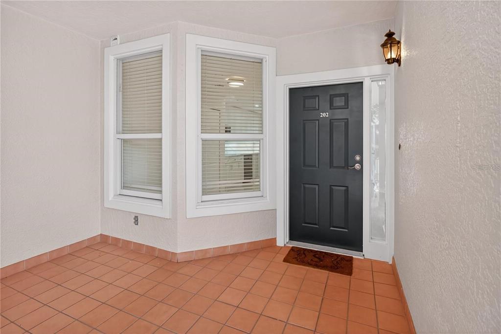 A covered entryway features a black front door, tiled flooring, and two large windows — 5430 EAGLES POINT CIRCLE UNIT 202, SARASOTA, FL