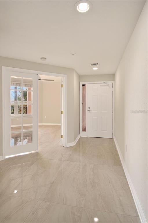 A bright entryway features light-colored tile flooring, a white front door, and glass French doors — 5430 EAGLES POINT CIRCLE UNIT 202, SARASOTA, FL