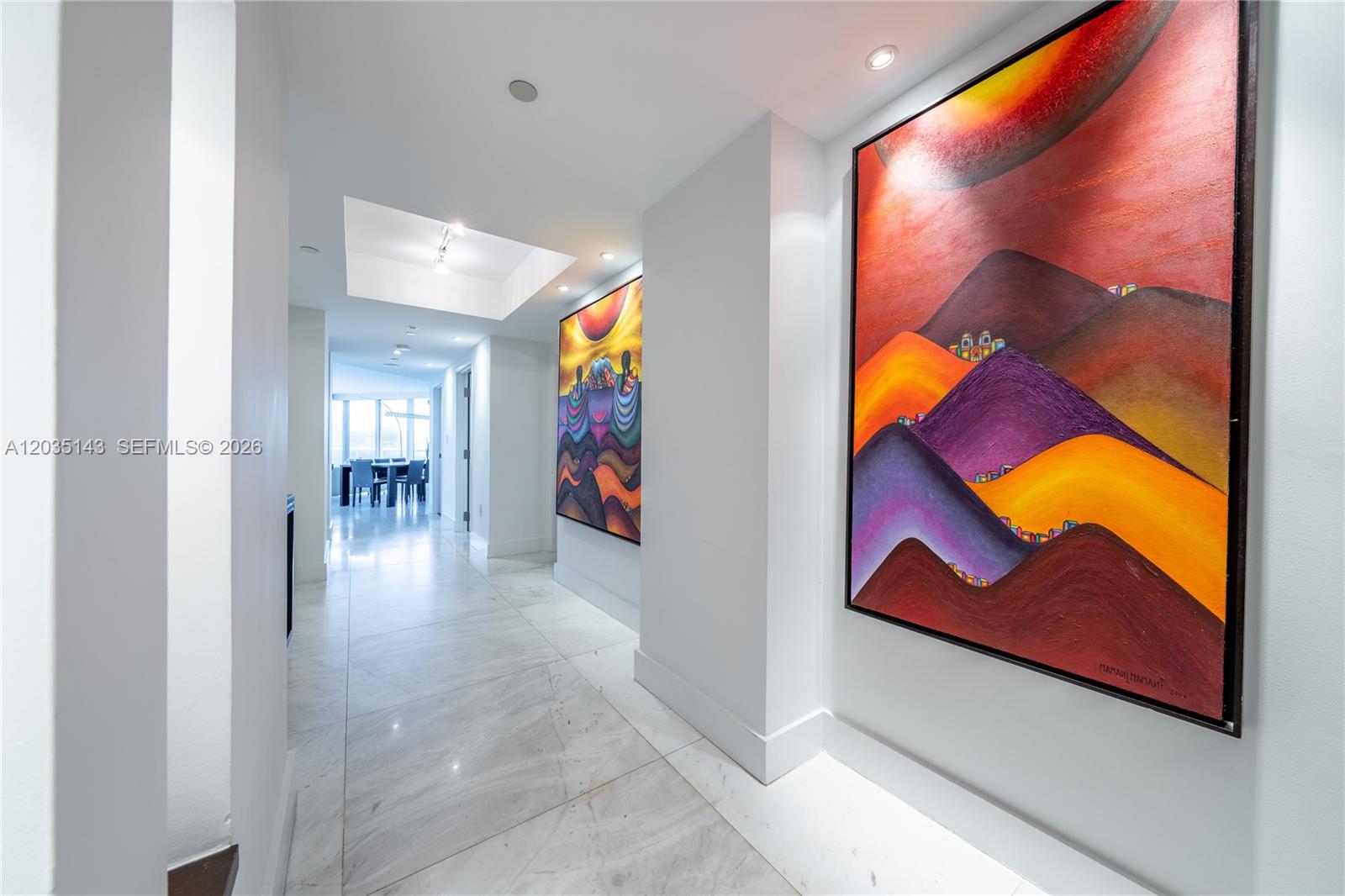 A bright hallway with marble floors features two large, colorful landscape paintings on white walls — 9401 Collins Ave # 403, Surfside FL 33154, SURFSIDE, FL