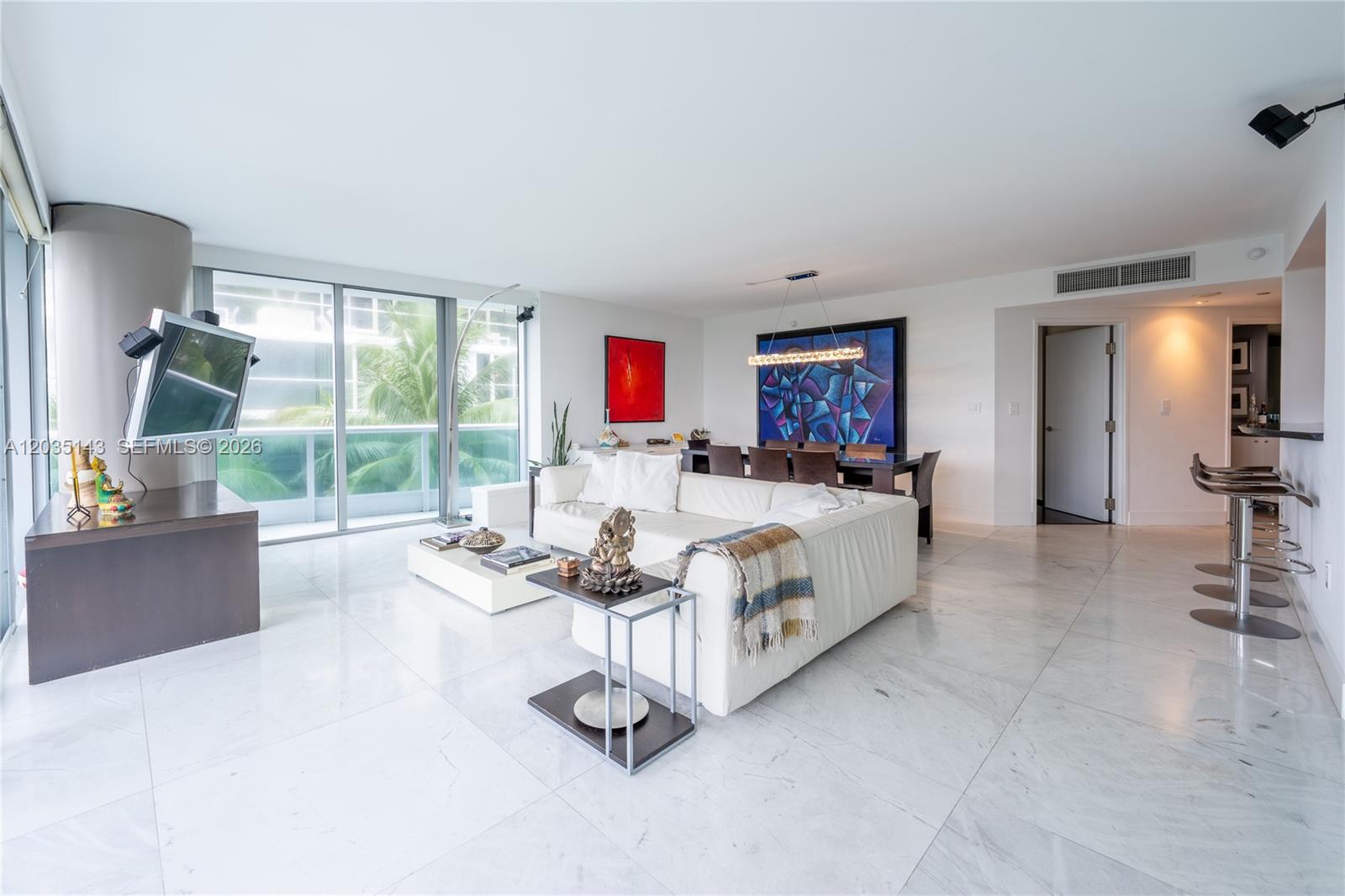 A modern living and dining area features white marble floors, a white sectional, and balcony views — 9401 Collins Ave # 403, Surfside FL 33154, SURFSIDE, FL