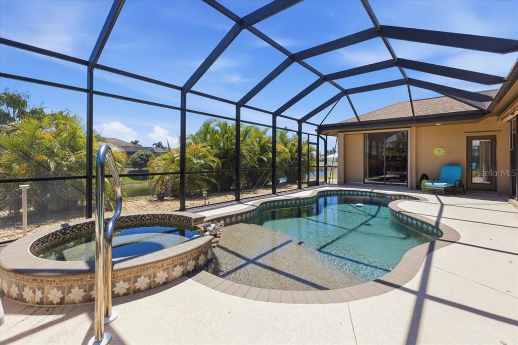 A screened-in patio features a swimming pool with an attached hot tub and tile coping — 19 MEDALIST WAY, ROTONDA WEST, FL