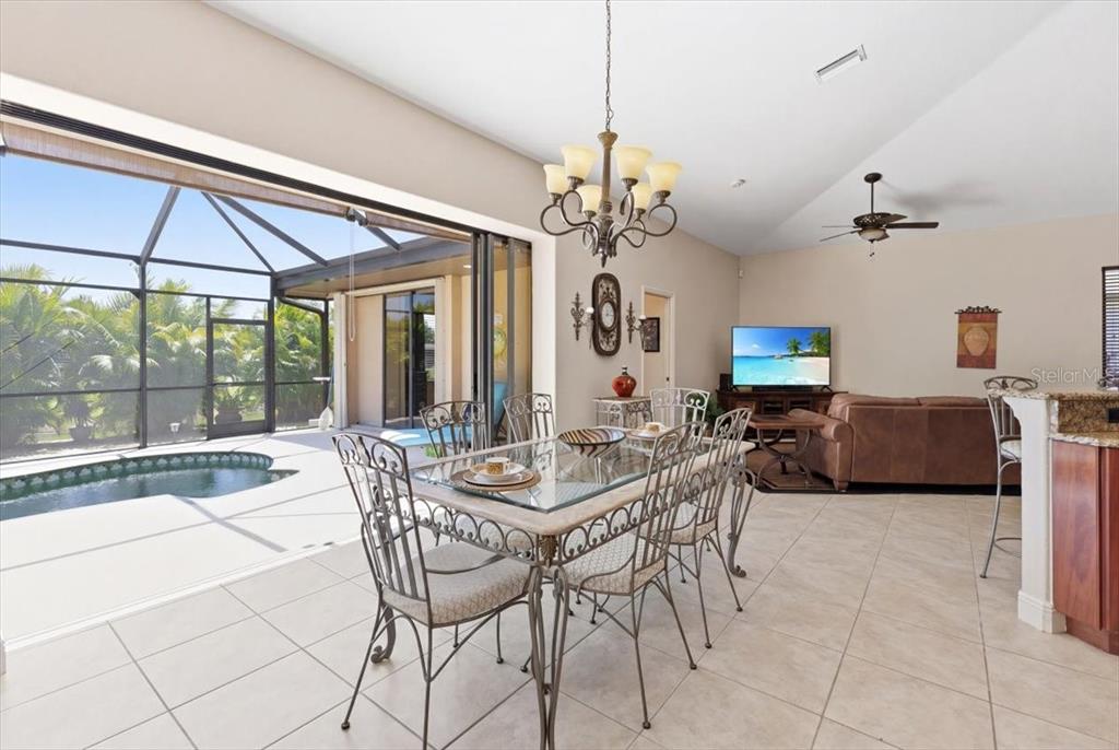A dining area with a glass table opens to a screened-in pool patio — 19 MEDALIST WAY, ROTONDA WEST, FL