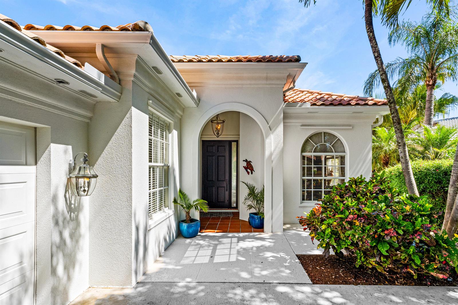 The exterior of a white stucco house features a tiled roof, arched entryway, and landscaping — 4983 Garden Drive, Delray Beach FL 33445, DELRAY BEACH, FL