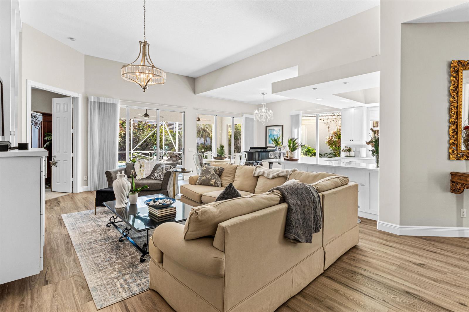A spacious living room features a beige sectional sofa, wood-look flooring, and large glass doors — 4983 Garden Drive, Delray Beach FL 33445, DELRAY BEACH, FL