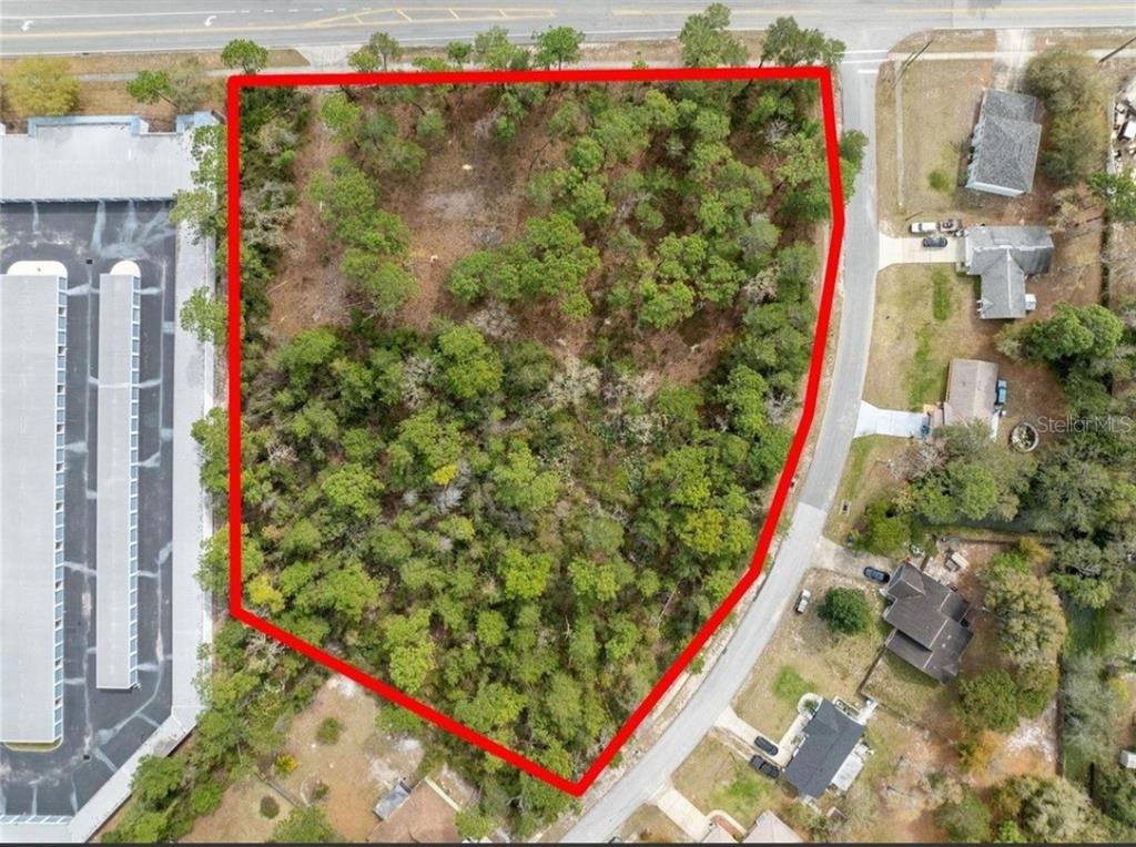 An aerial view shows a wooded, irregularly shaped vacant lot outlined in red — 1370 COURTLAND BLVD, DELTONA, FL