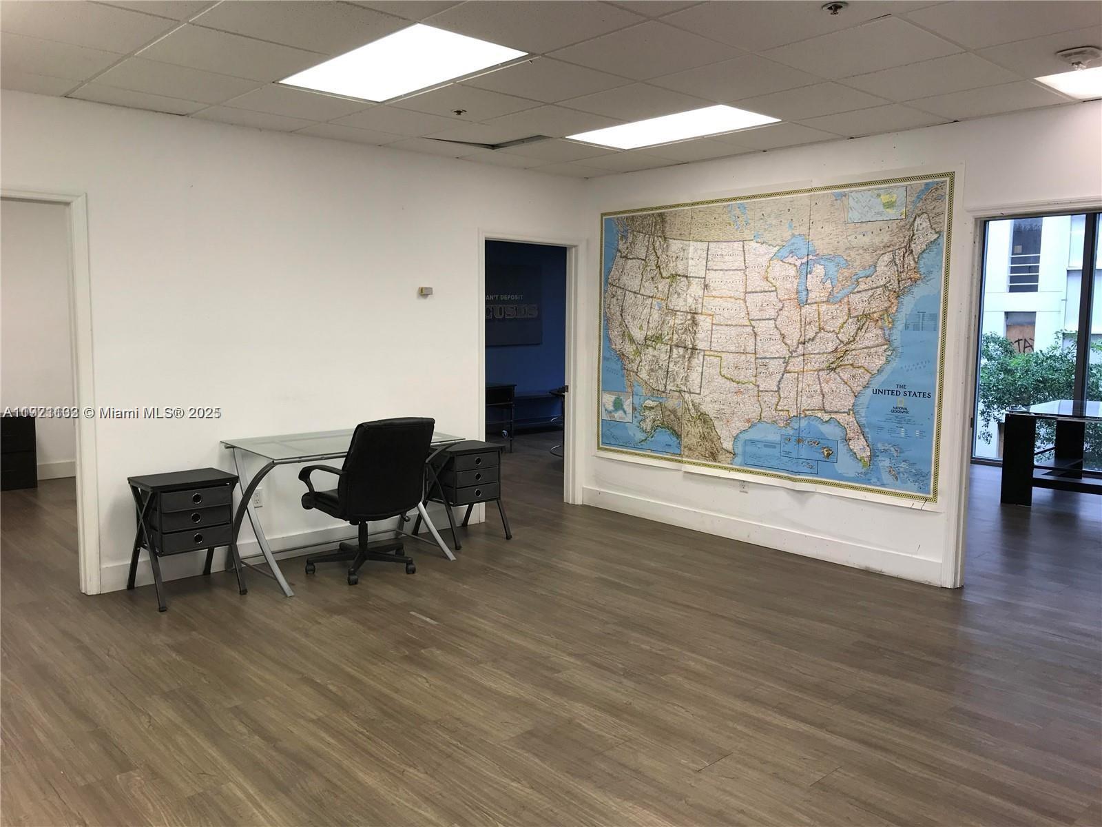 An office space features a glass desk, a black chair, and a large wall map — 150 SE 2nd Ave, Miami FL 33131, MIAMI, FL