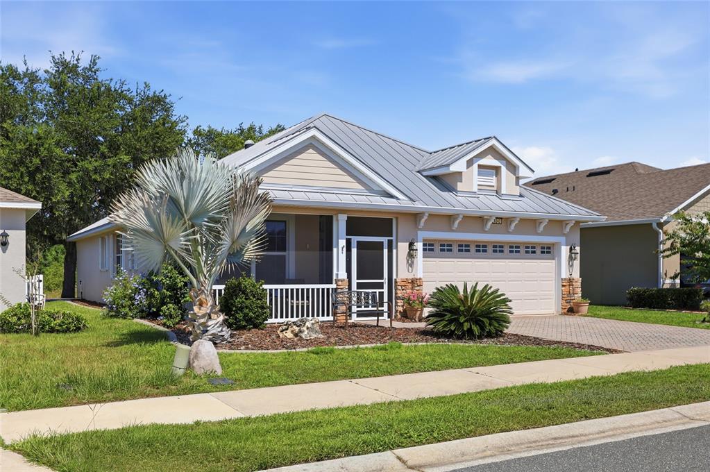A single-story house with a metal roof, a screened front porch, and a two-car garage — 6342 SANDERS GROVE CIRCLE, OKAHUMPKA, FL