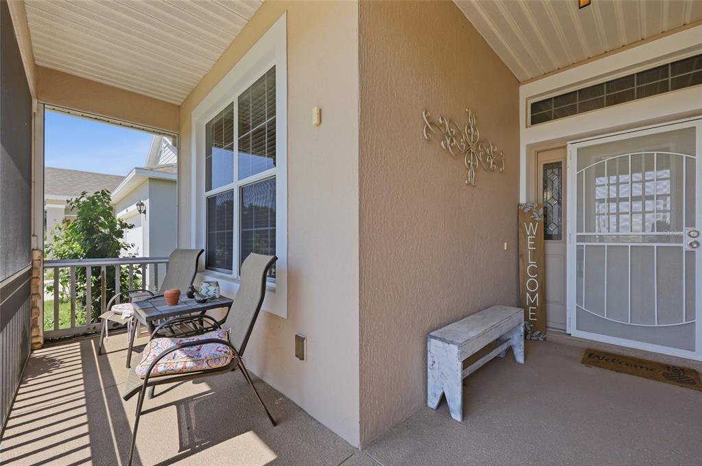 A covered front porch features a seating area, a bench, and a screen door — 6342 SANDERS GROVE CIRCLE, OKAHUMPKA, FL