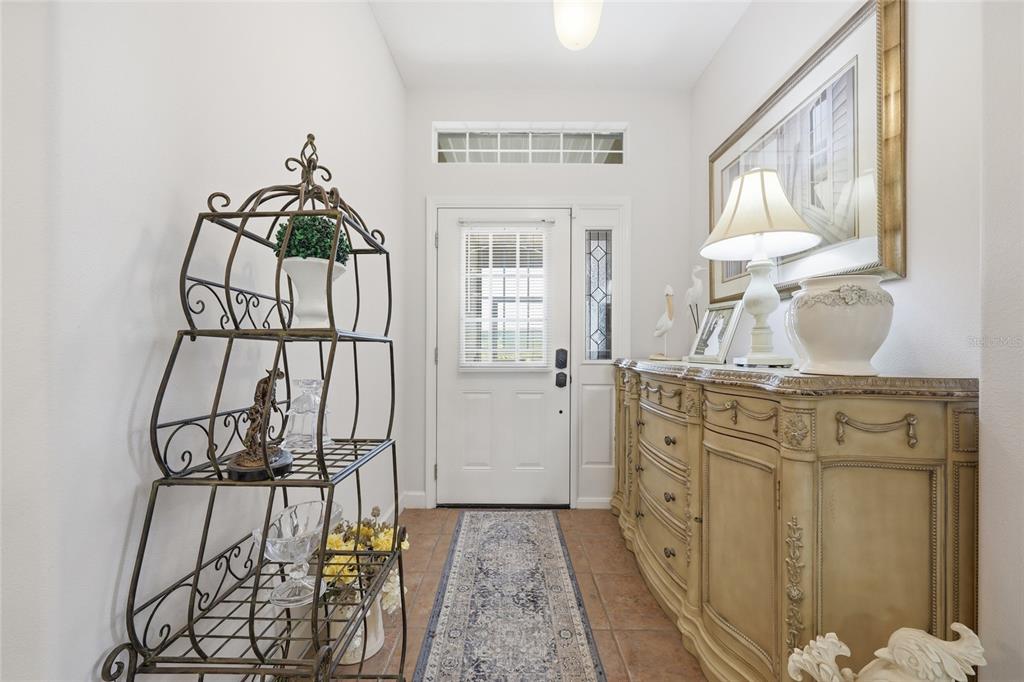 An entryway features a metal shelf, a wooden dresser, a runner rug, and a front door — 6342 SANDERS GROVE CIRCLE, OKAHUMPKA, FL