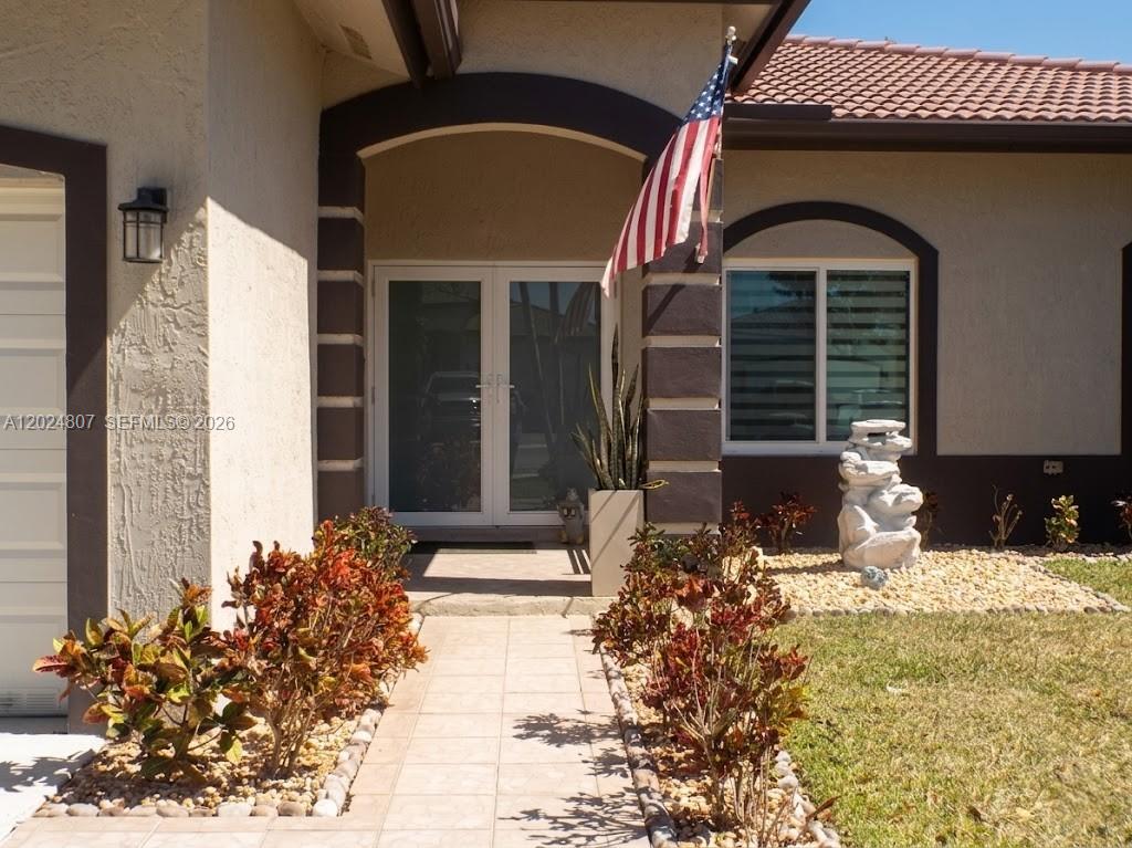 A paved walkway leads to the front entrance of a house with a flag — 14127 SW 161st Pl, Miami FL 33196, MIAMI, FL
