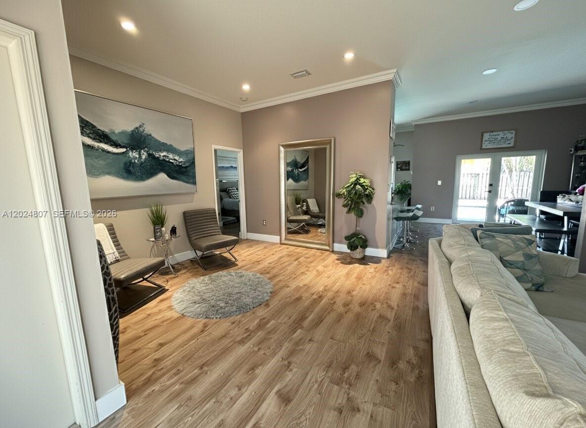 A living room features light wood-look flooring, a large wall mirror, and a grey sofa — 14127 SW 161st Pl, Miami FL 33196, MIAMI, FL