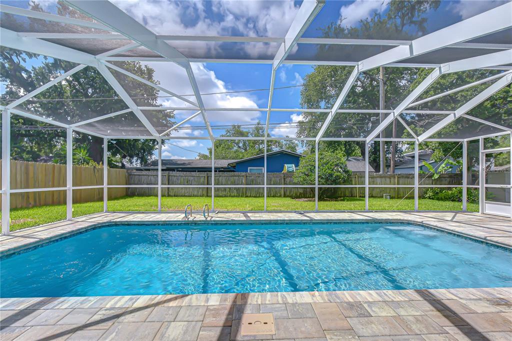 A rectangular swimming pool sits inside a screened-in enclosure with a paved patio and lawn — 2167 LAKEVIEW ROAD, CLEARWATER, FL