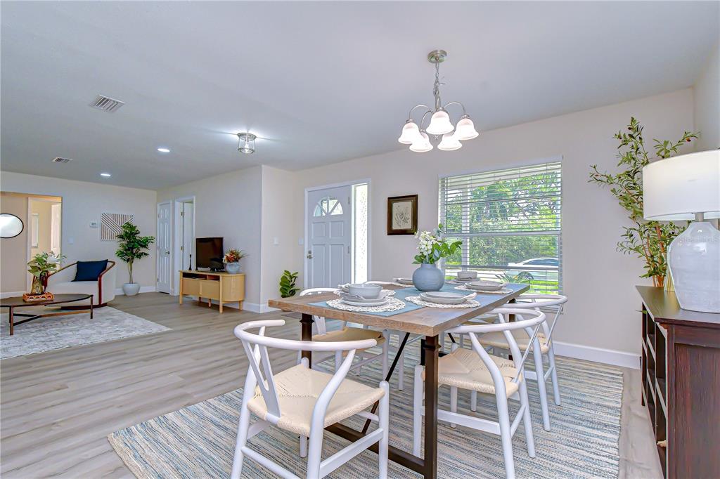 A dining area with a wooden table and white chairs sits adjacent to a living room — 2167 LAKEVIEW ROAD, CLEARWATER, FL