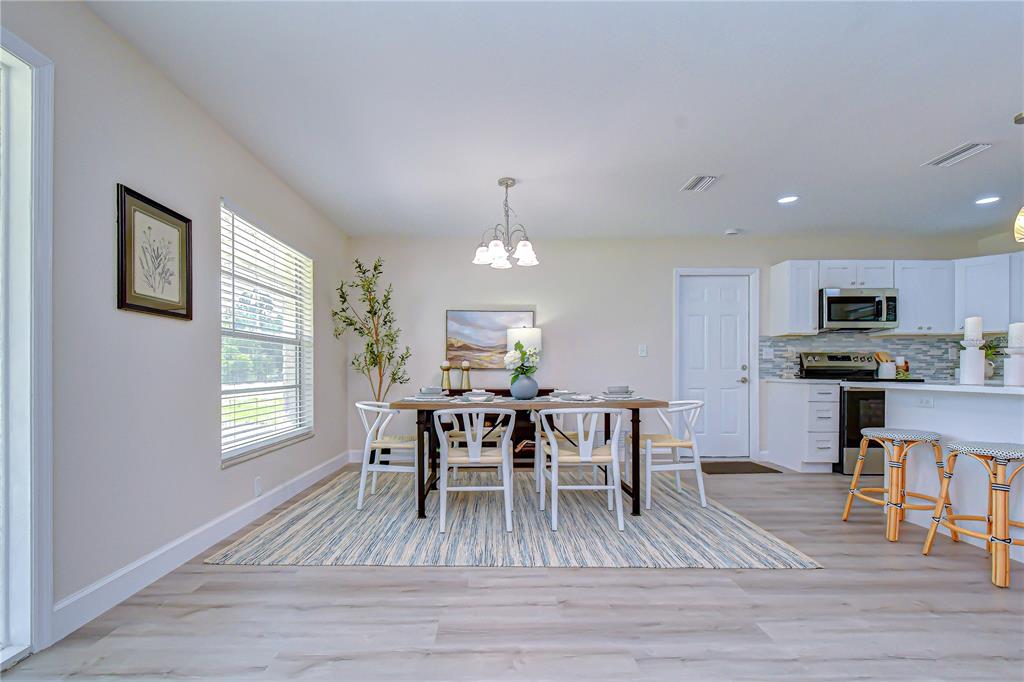 A dining area with a wooden table, white chairs, and a rug near a kitchen — 2167 LAKEVIEW ROAD, CLEARWATER, FL