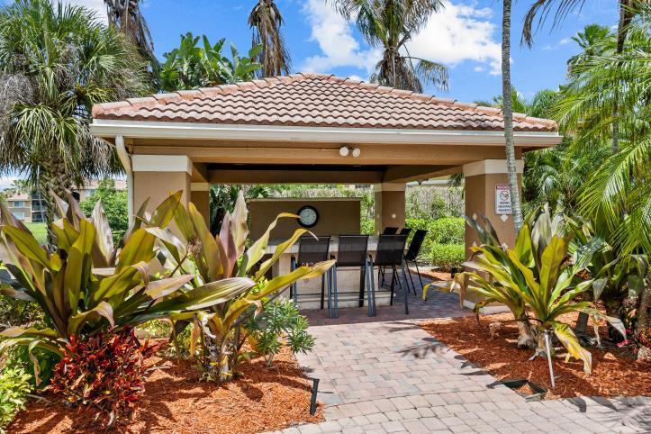 A covered outdoor pavilion features a stone bar with stools on a brick patio — 3721 NW Mediterranean Lane # 304, Jensen Beach FL 34957, JENSEN BEACH, FL