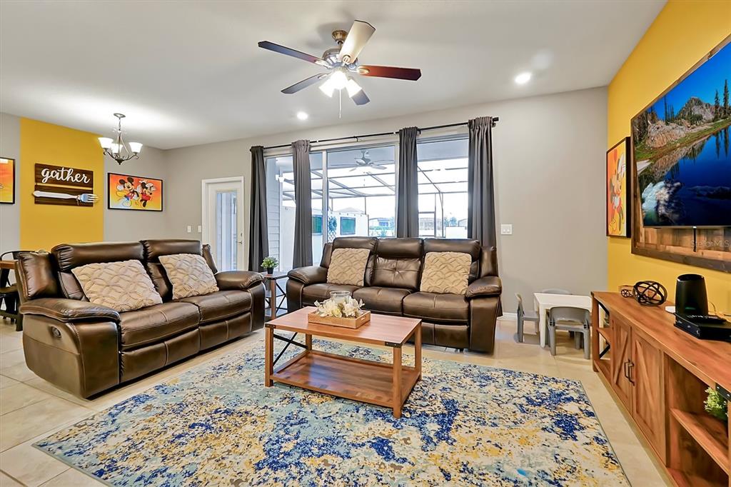 A living room features brown leather sofas, a wooden coffee table, and yellow accent walls — 7578 OAK SPRING LANE, DAVENPORT, FL