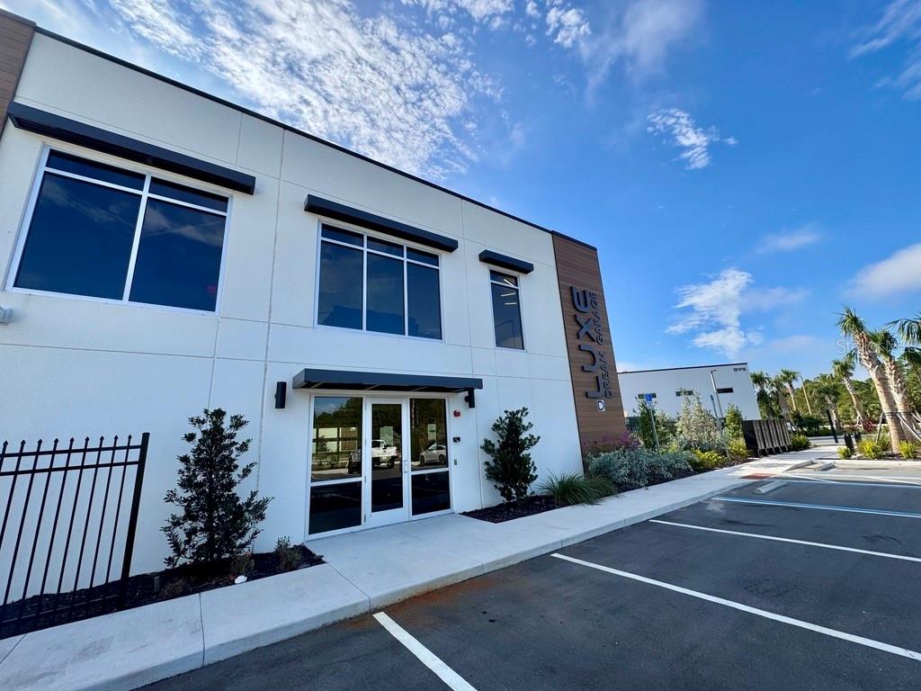 A modern two-story commercial building with a glass entrance and parking lot in front — 5421 COMMUNICATIONS PARKWAY UNIT 40, LAKEWOOD RANCH, FL