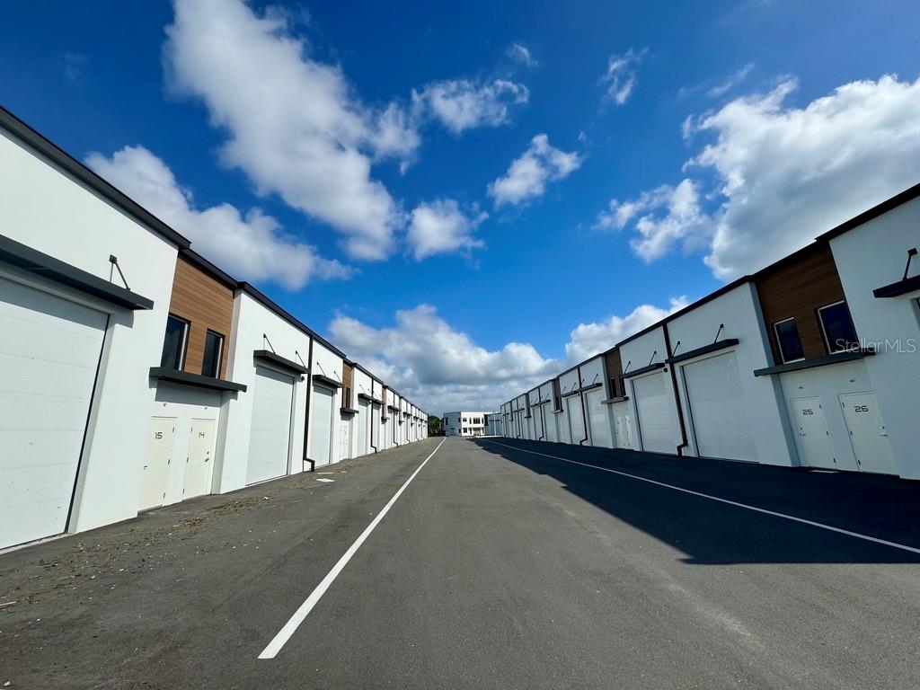 A paved driveway runs between two rows of modern, white commercial storage units under a sky — 5421 COMMUNICATIONS PARKWAY UNIT 40, LAKEWOOD RANCH, FL