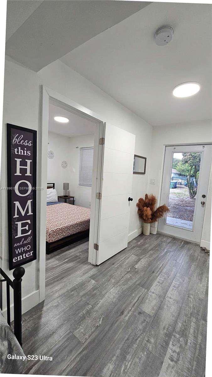 A hallway with wood-look flooring leads to a bedroom and an exterior door — 6743 NW 4th Ave, Miami FL 33150, MIAMI, FL