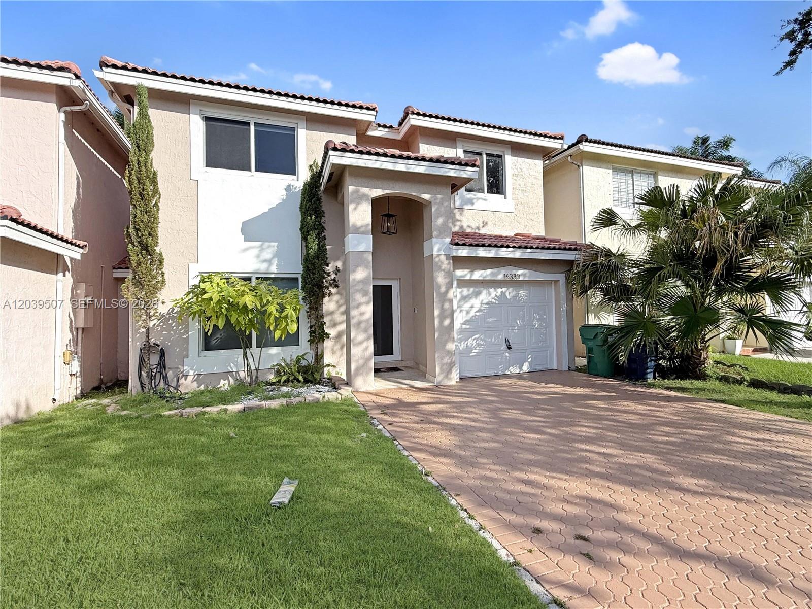 A two-story stucco house features a tiled roof, a paved driveway, and a front entrance — 16330 SW 102nd St, Miami FL 33196, MIAMI, FL