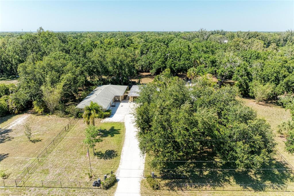 An aerial view shows a single-story house with a long driveway surrounded by dense trees — 2515 49TH STREET, SARASOTA, FL