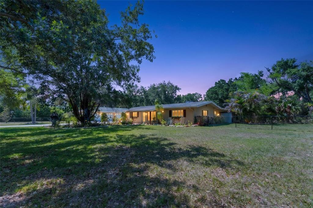 A single-story house with a large lawn and mature trees under a twilight sky — 2515 49TH STREET, SARASOTA, FL