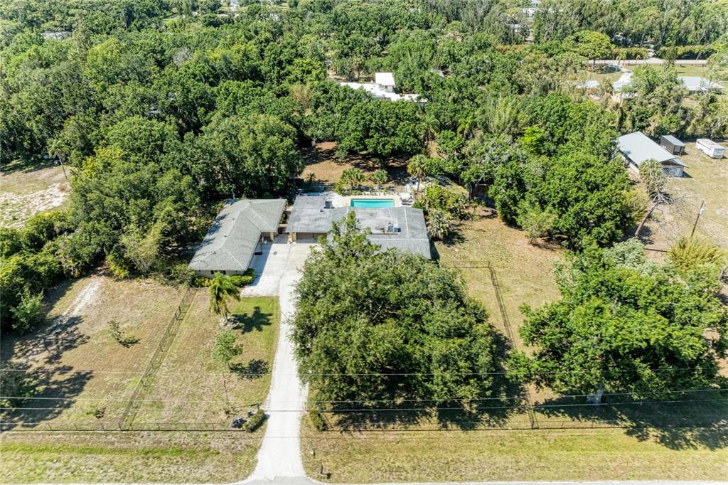 An aerial view shows a house with a pool, a long driveway, and surrounding trees — 2515 49TH STREET, SARASOTA, FL