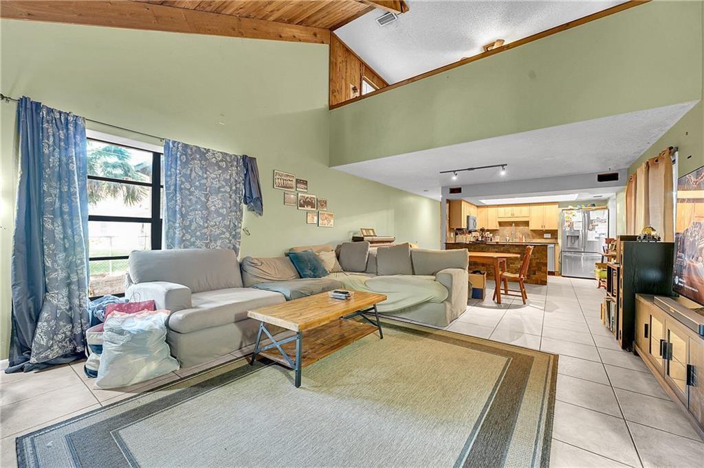A living room with a vaulted ceiling, sectional sofa, and an open kitchen in back — 7103 Arthurs Road, Fort Pierce FL 34951, FORT PIERCE, FL