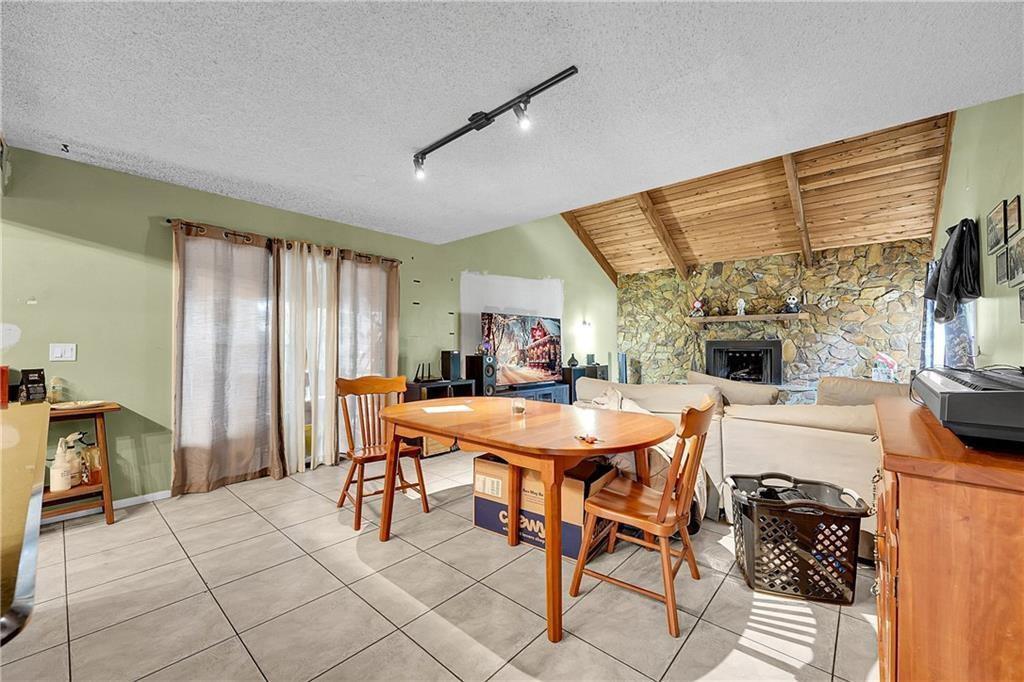 A dining area with tile floors, a wooden table, and a stone fireplace — 7103 Arthurs Road, Fort Pierce FL 34951, FORT PIERCE, FL