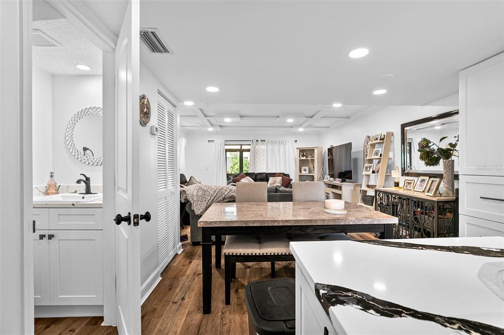 A dining area with a marble-topped table sits adjacent to a bathroom and living room — 7223 CLOISTER DRIVE UNIT 111, SARASOTA, FL