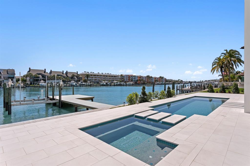 A modern swimming pool and spa overlook a waterfront canal with boat docks and buildings — 500 BARCELONA DRIVE, TIERRA VERDE, FL