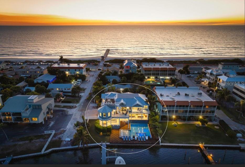 An aerial view of a waterfront house with a pool, deck, and dock at sunset — 110 10TH STREET S, BRADENTON BEACH, FL