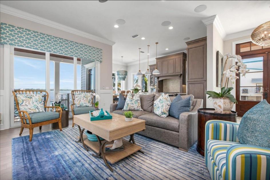 A living room features a grey sofa, patterned armchairs, a wooden coffee table, and water views — 110 10TH STREET S, BRADENTON BEACH, FL