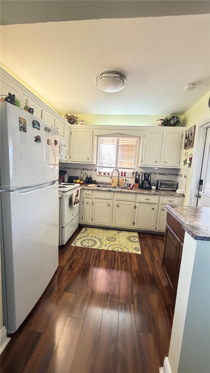 A kitchen features white cabinets, stainless steel appliances, a sink, and dark wood flooring — 5300 Washington St # D309, Hollywood FL 33021, HOLLYWOOD, FL