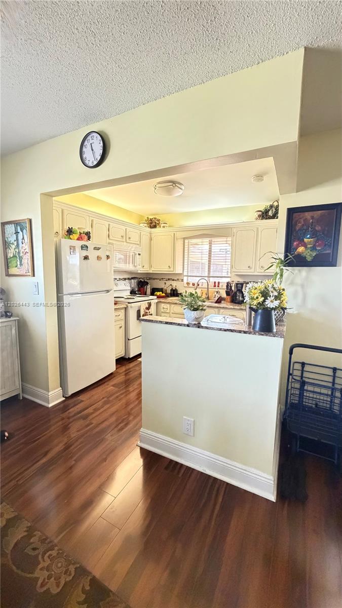 A kitchen features white cabinetry, a white refrigerator, and dark wood-look flooring — 5300 Washington St # D309, Hollywood FL 33021, HOLLYWOOD, FL