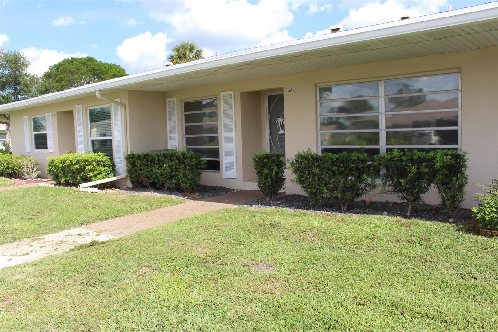 A single-story beige house with a white roof, shuttered windows, and a front lawn — 8861 Bella Vista Drive, Boca Raton FL 33433, BOCA RATON, FL