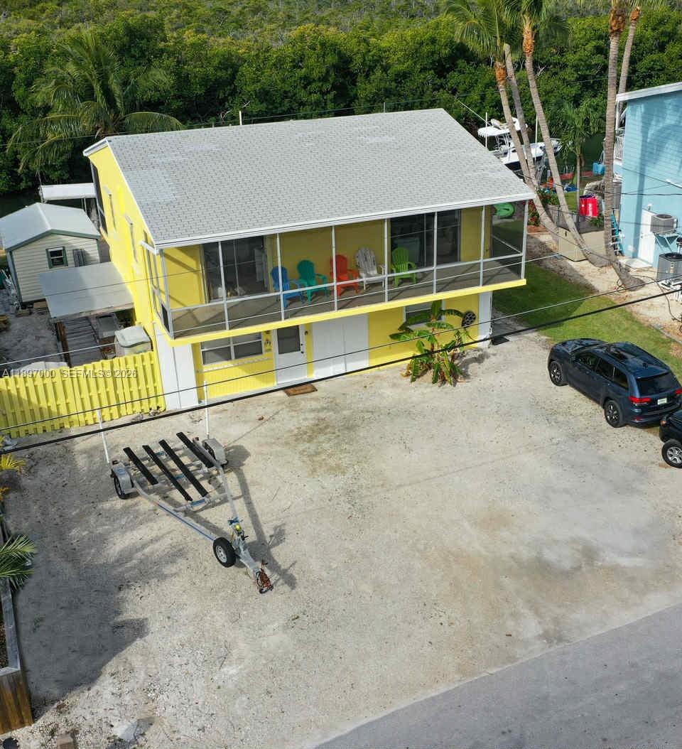 An elevated yellow house with a screened porch sits on a gravel lot with a trailer — 164 Venetian Dr, Islamorada FL 33036, ISLAMORADA, FL