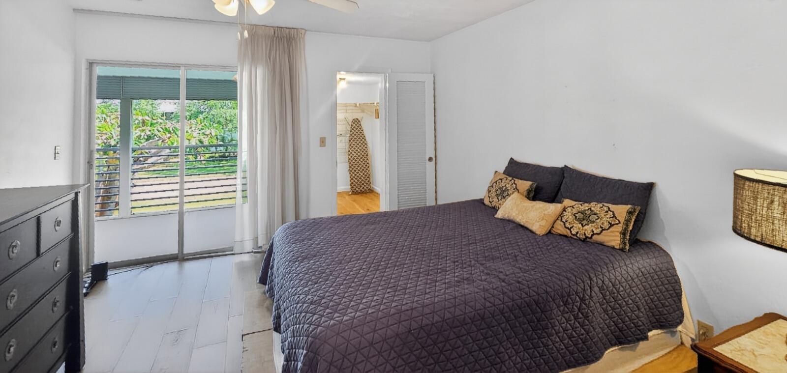 A bedroom features a dark quilt on the bed, a dresser, and a sliding glass door — 8 Garden Street # 206r, Tequesta FL 33469, TEQUESTA, FL