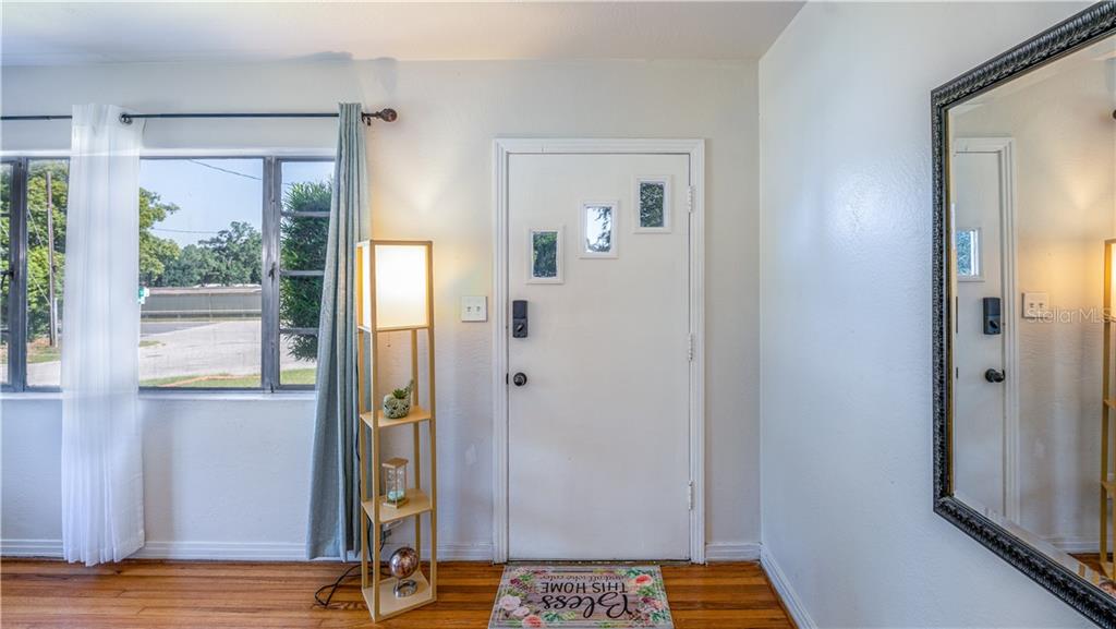 An entryway features a white front door, a floor lamp, and a large wall mirror — 2014 NEWMAN STREET, ORLANDO, FL