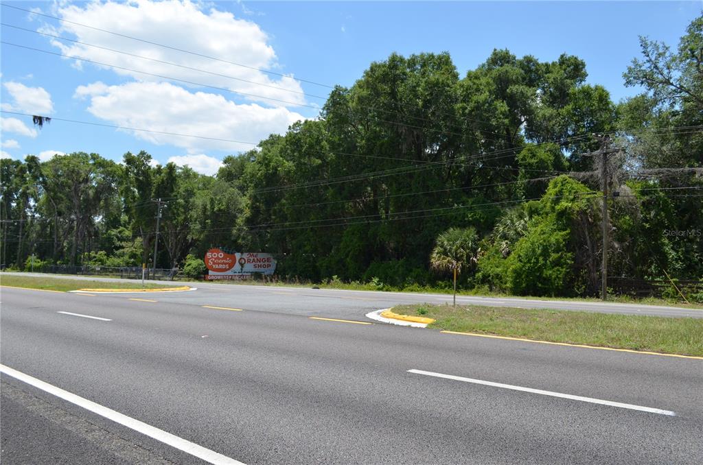 A paved road runs in front of a wooded lot with a small sign — TBD N US HWY 301, CITRA, FL